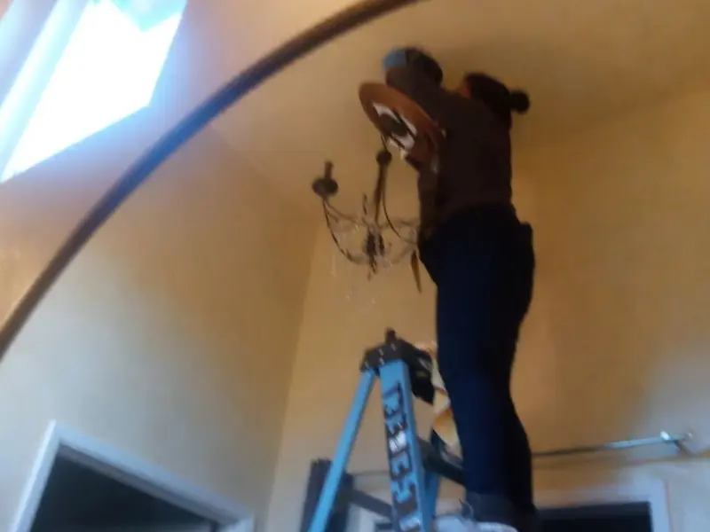 Electrician installing a chandelier in a Imlay residence